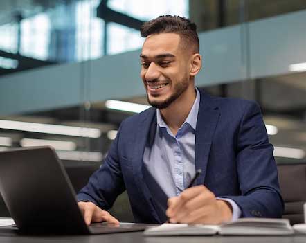 a man smiling and working at his computer in an office