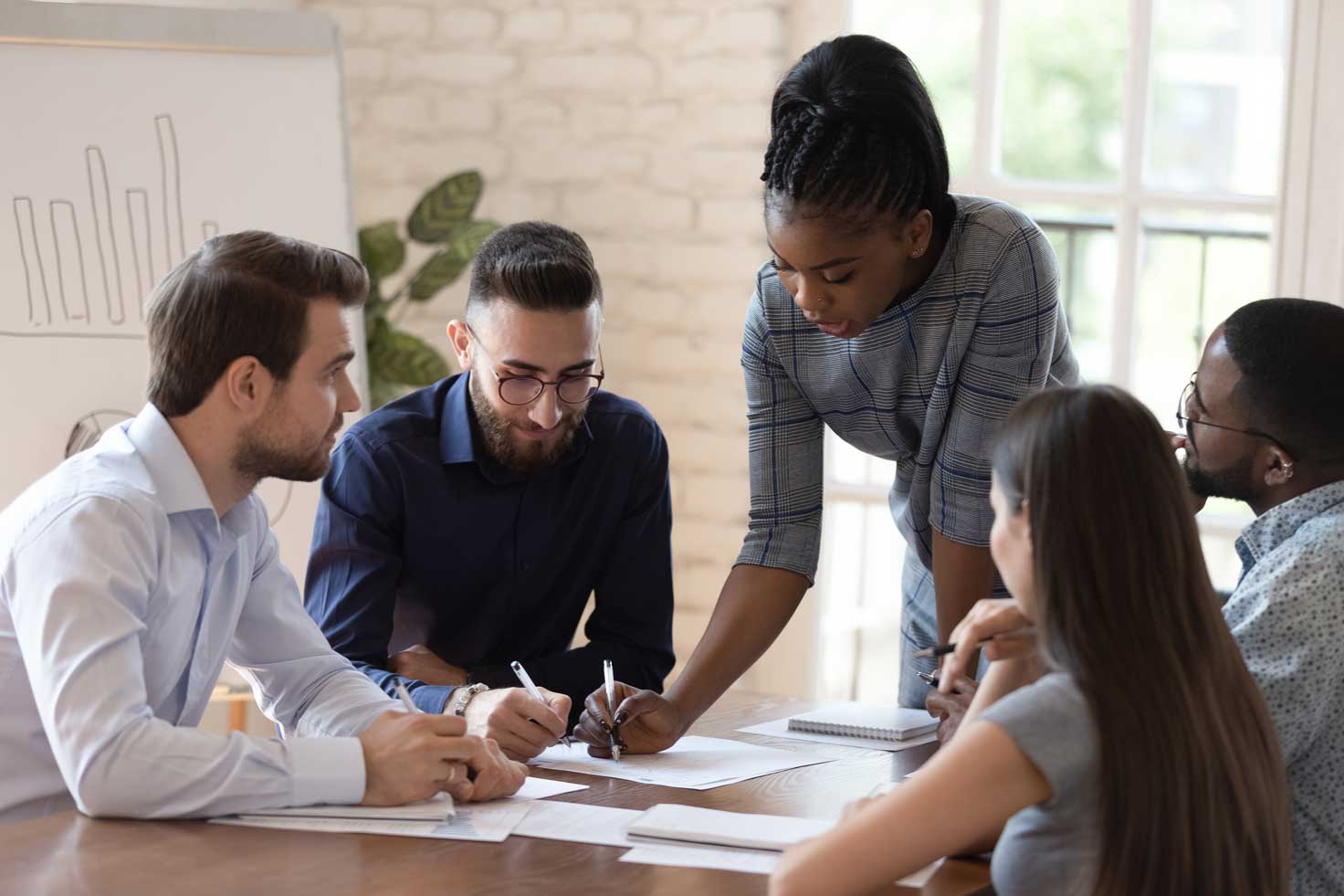 a woman teaching at a table with other adults looking at papers