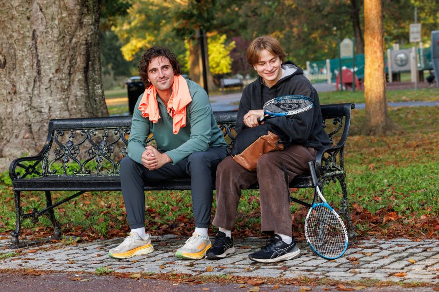 a father and son sit on a park bench