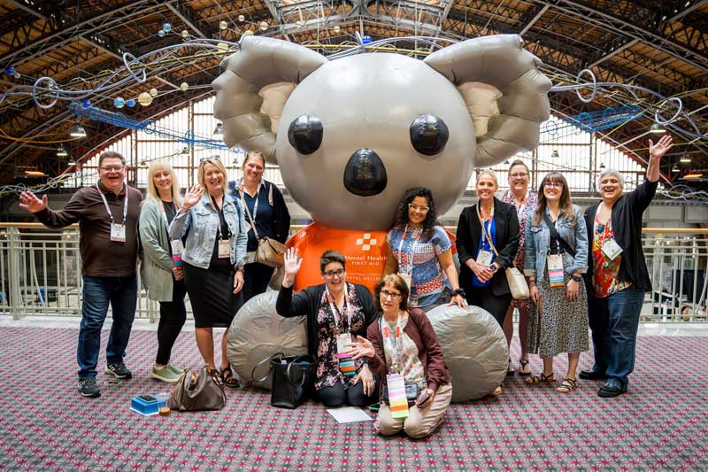 a group of people around a giant blow up koala bear wearing an MHFA shirt