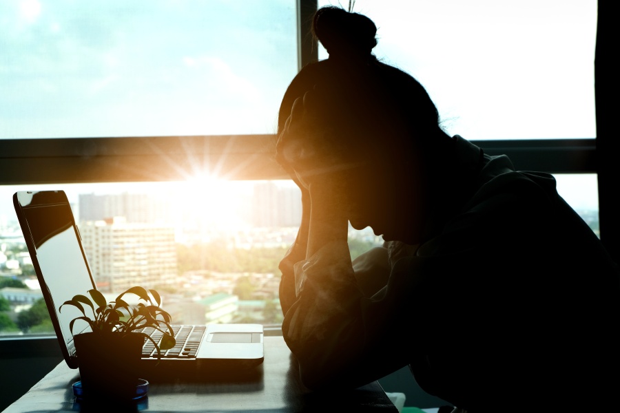 a woman is doomscrolling at her desk which is visibly affecting her mental health