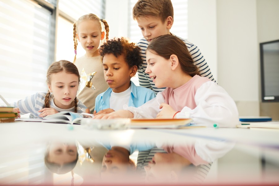 students crowd around a desk and book