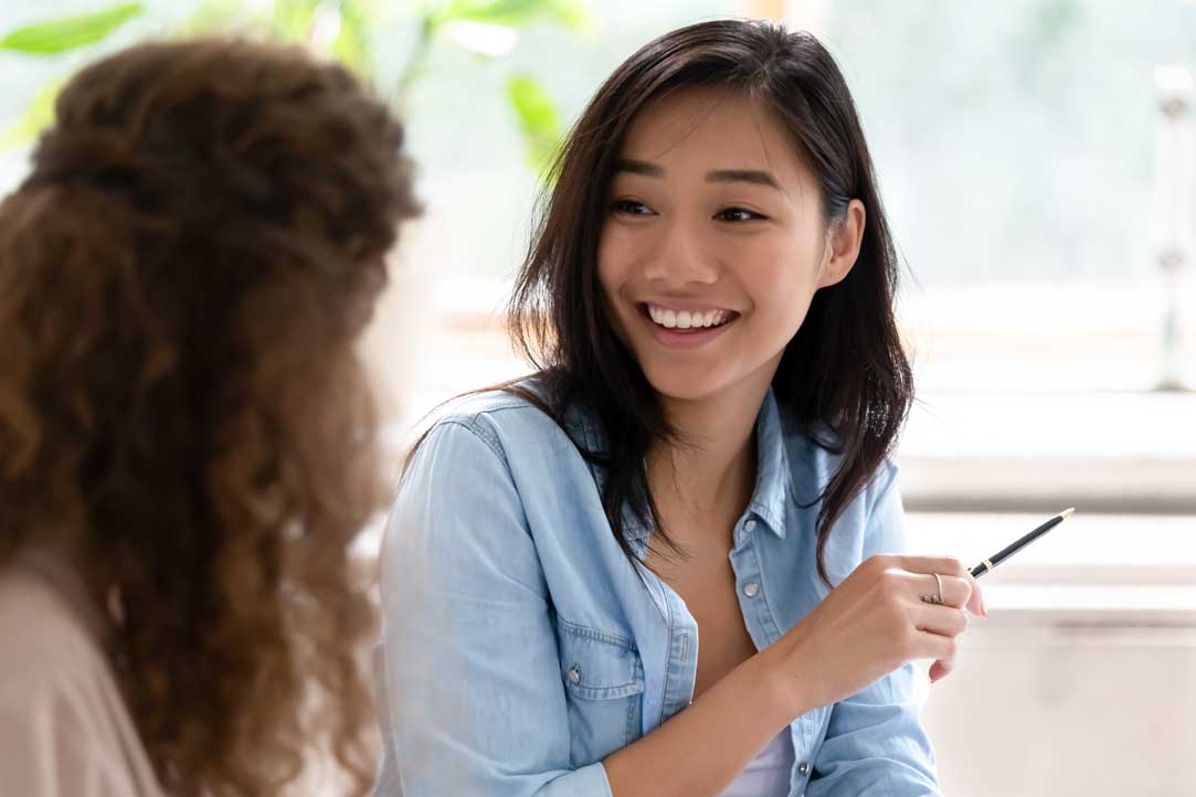 a college student smiles and talks to another student in a classroom