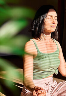 a woman sitting with legs crossed and eyes closed