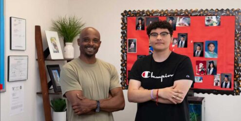 two men standing next to each other and smiling in a classroom