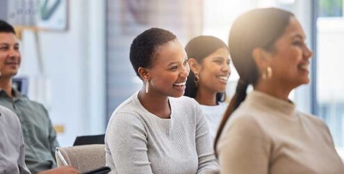 employees sit in a meeting smiling