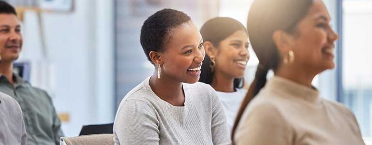 employees sit in a meeting smiling