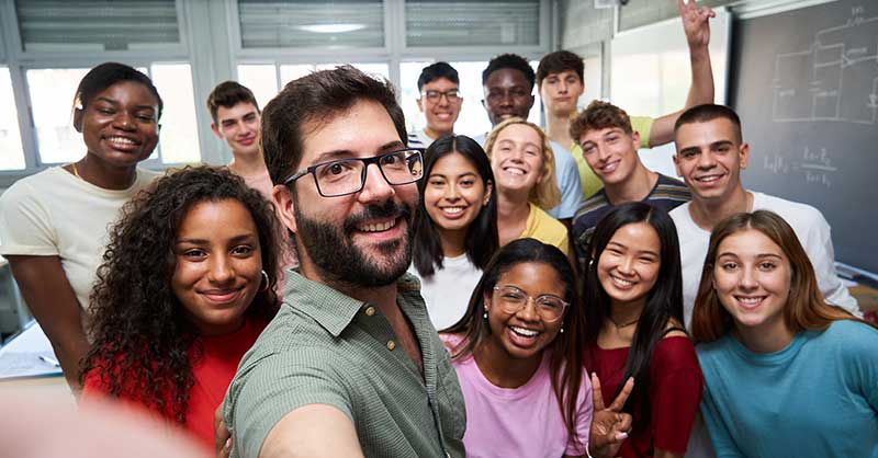 a group of college students take a selfie in a classroom